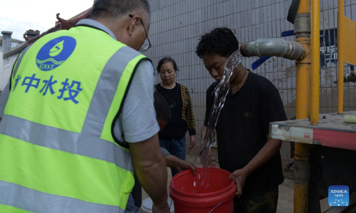A worker of the water resources department delivers drinking water to villagers in Xinglongshan Village, Yuzhong County of northwest China's Gansu Province, Aug. 11, 2025. Roads damaged by mountain torrents in Yuzhong County reopened on Sunday and power supply has been restored following the disaster that left 13 dead and 30 missing. (Xinhua/Fan Peishen)