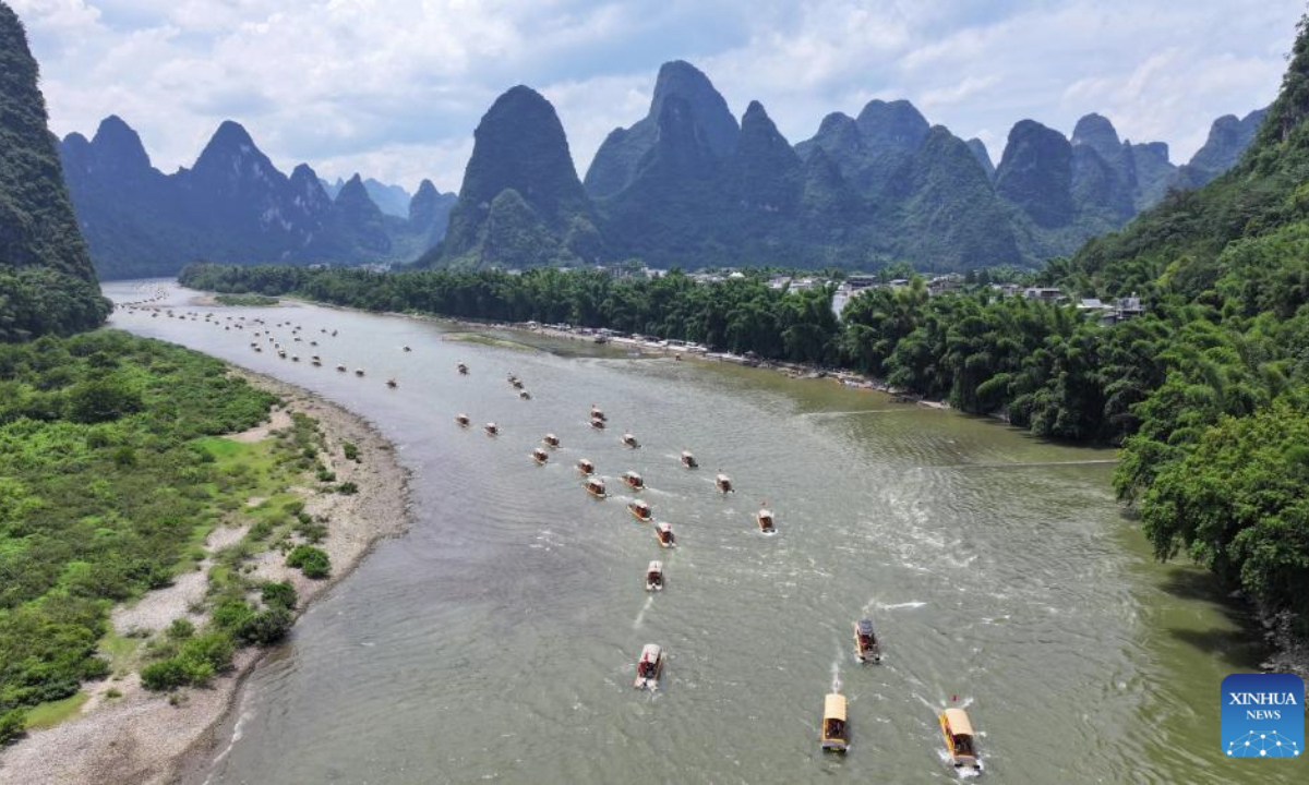 An aerial drone photo taken on Aug. 10, 2025 shows tourists enjoying the scenery on bamboo rafts along the Lijiang river in Yangshuo County, south China's Guangxi Zhuang Autonomous Region. Scenic areas across China have entered peak season for tourism during summer vacation. (Photo by He Hongfu/Xinhua)