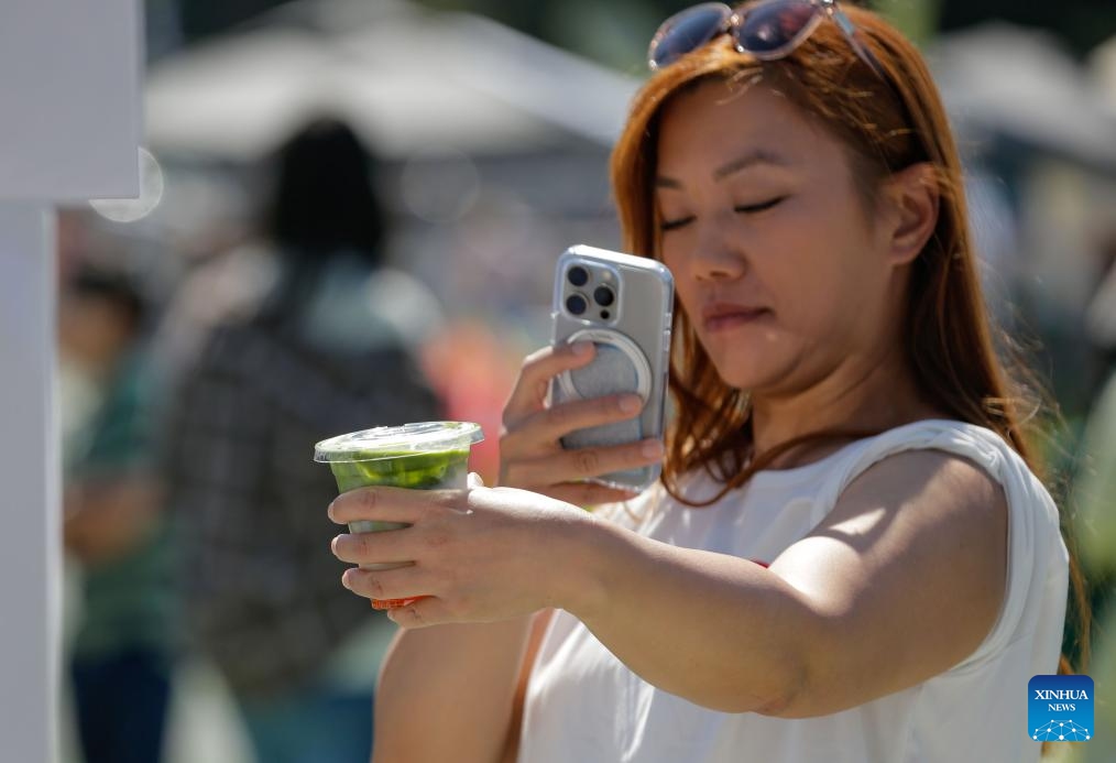 A woman takes a photo with her bubble tea during the 2025 Bubble Tea Festival in Burnaby, British Columbia, Canada, on Aug. 10, 2025. The festival showcases over a hundred kinds of bubble tea, attracting bubble tea lovers to the event. (Photo by Liang Sen/Xinhua)