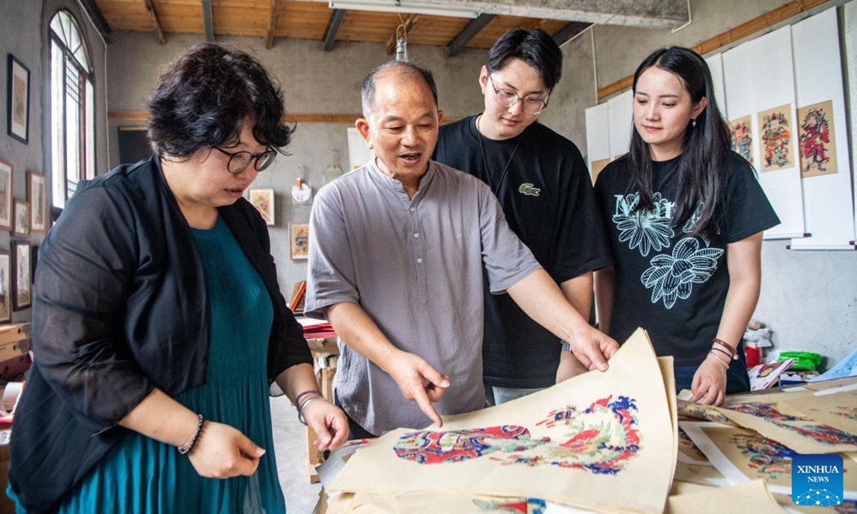 Xu Jiahui (2nd L), a representative inheritor of Liangping New Year Woodblock Prints, introduces this craft to students at his workshop in Liangping District of southwest China's Chongqing Municipality, Aug. 10, 2025. Hanging New Year pictures is one of the folk activities for Chinese people to celebrate the Spring Festival. A summer vacation experience class of Liangping New Year Woodblock Prints, a national intangible cultural heritage item, opened here on Sunday. (Xinhua/Tang Yi)