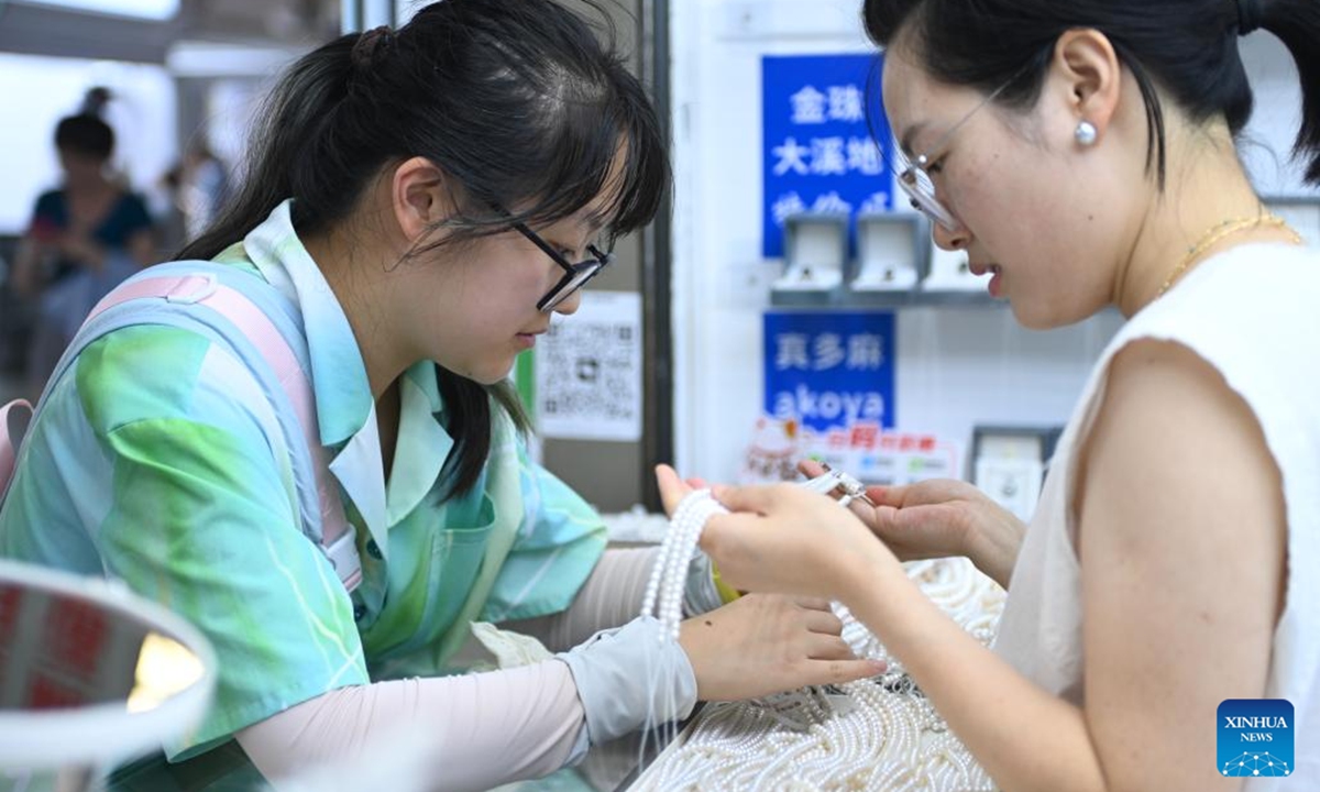 A shopkeeper (R) introduces pearl jewelry to a customer at a trading center for jewelry products in Shanxiahu Town, Zhuji City of east China's Zhejiang Province, Aug. 9, 2025. Shanxiahu Town of Zhejiang Province is renowned for its pearl industry that ranges from pearl farming, processing, trading to cultural tourism. (Xinhua/Mao Zhu)