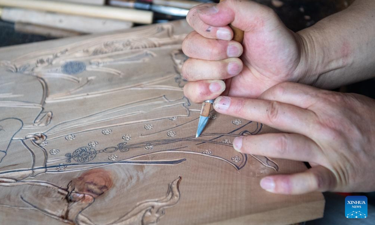 Xu Jiahui, a representative inheritor of Liangping New Year Woodblock Prints, demonstrates the engraving process to students at his workshop in Liangping District of southwest China's Chongqing Municipality, Aug. 10, 2025. Hanging New Year pictures is one of the folk activities for Chinese people to celebrate the Spring Festival. A summer vacation experience class of Liangping New Year Woodblock Prints, a national intangible cultural heritage item, opened here on Sunday. (Xinhua/Tang Yi)