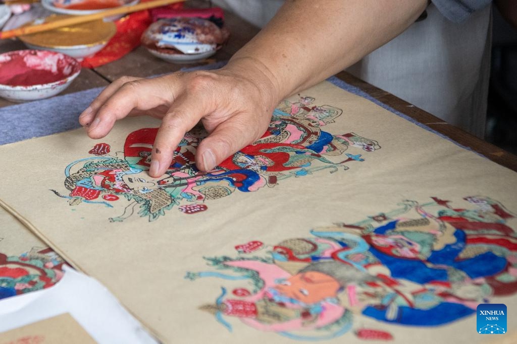 Xu Jiahui, a representative inheritor of Liangping New Year Woodblock Prints, executes the facial rendering process of a woodblock painting at his workshop in Liangping District of southwest China's Chongqing Municipality, Aug. 10, 2025. Hanging New Year pictures is one of the folk activities for Chinese people to celebrate the Spring Festival. A summer vacation experience class of Liangping New Year Woodblock Prints, a national intangible cultural heritage item, opened here on Sunday. (Xinhua/Tang Yi)