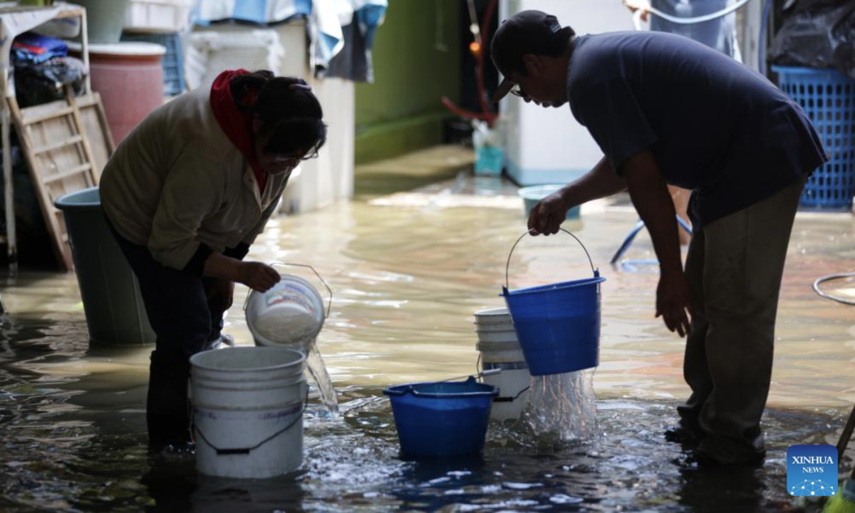 People drain water in their house in Nezahualcoyotl, a city 20 kilometers east of Mexico City center, Mexico, Aug. 12, 2025. Mexico City has experienced rare heavy rainfall in recent days, causing flood in the city and some surrounding areas. The short-term rainfall on Sunday in the city center broke the record set in 1952, report said. (Photo by Francisco Canedo/Xinhua)