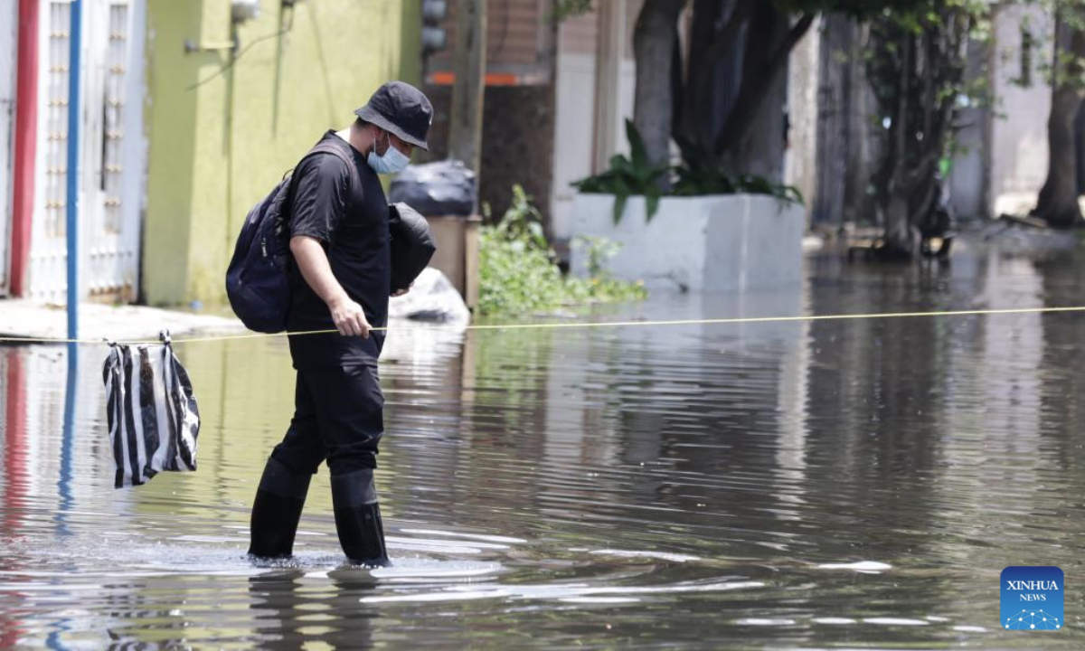 A man wades through flood water in Nezahualcoyotl, a city 20 kilometers east of Mexico City center, Mexico, Aug. 12, 2025. Mexico City has experienced rare heavy rainfall in recent days, causing flood in the city and some surrounding areas. The short-term rainfall on Sunday in the city center broke the record set in 1952, report said. (Photo by Francisco Canedo/Xinhua)