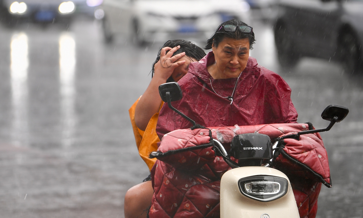 Beijing residents ride an electric motorcycle in the heavy rain on August 12, 2025. Beijing Meteorological Observatory issued multiple warnings, urging residents to take precautions against heavy rainfall and severe convective weather. Photo: VCG