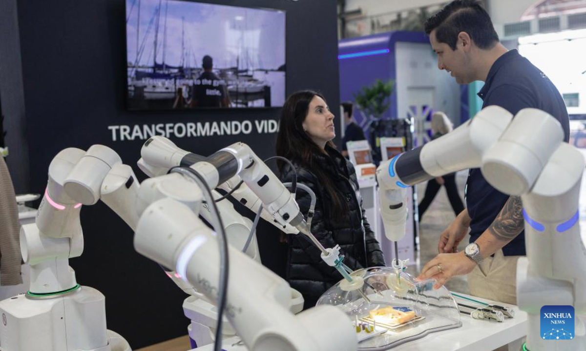 A visitor interacts with a demonstrator during a robotic surgery demonstration during Rio Innovation Week in Rio de Janeiro, Brazil, on Aug. 13, 2025. (Photo by Claudia Martini/Xinhua)