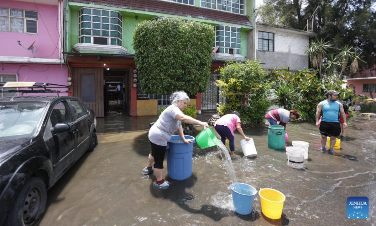 People drain water outside their houses in Nezahualcoyotl, a city 20 kilometers east of Mexico City center, Mexico, Aug. 12, 2025. Mexico City has experienced rare heavy rainfall in recent days, causing flood in the city and some surrounding areas. The short-term rainfall on Sunday in the city center broke the record set in 1952, report said. (Photo by Francisco Canedo/Xinhua)