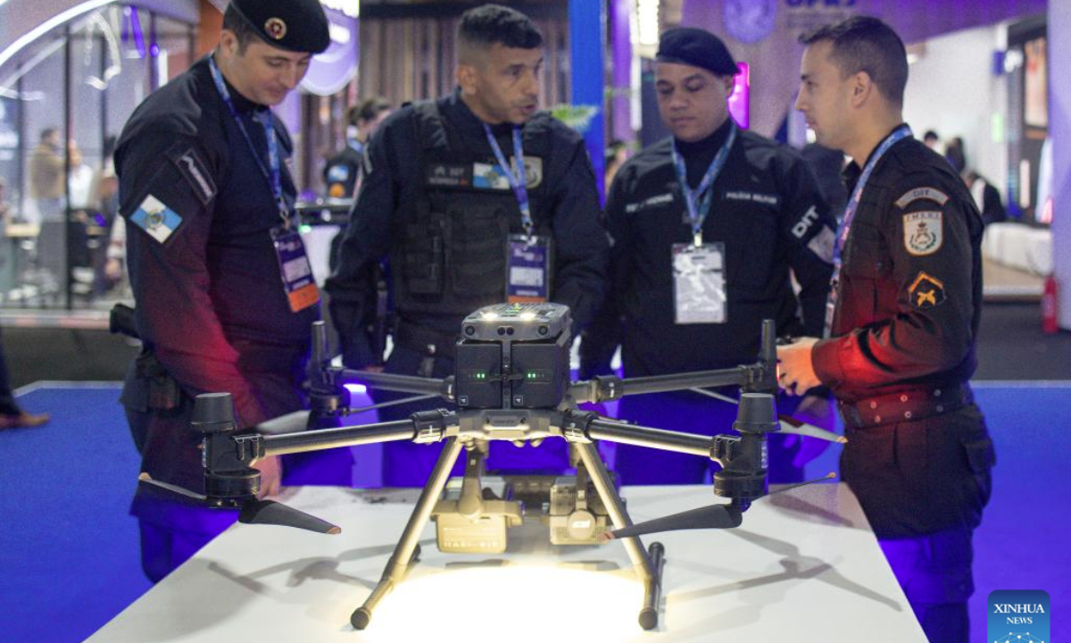 Visitors talk behind a police drone showcased during Rio Innovation Week in Rio de Janeiro, Brazil, on Aug. 13, 2025. (Photo by Claudia Martini/Xinhua)