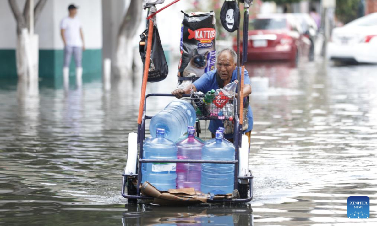 A man wades through flood water in Nezahualcoyotl, a city 20 kilometers east of Mexico City center, Mexico, Aug. 12, 2025. Mexico City has experienced rare heavy rainfall in recent days, causing flood in the city and some surrounding areas. The short-term rainfall on Sunday in the city center broke the record set in 1952, report said. (Photo by Francisco Canedo/Xinhua)