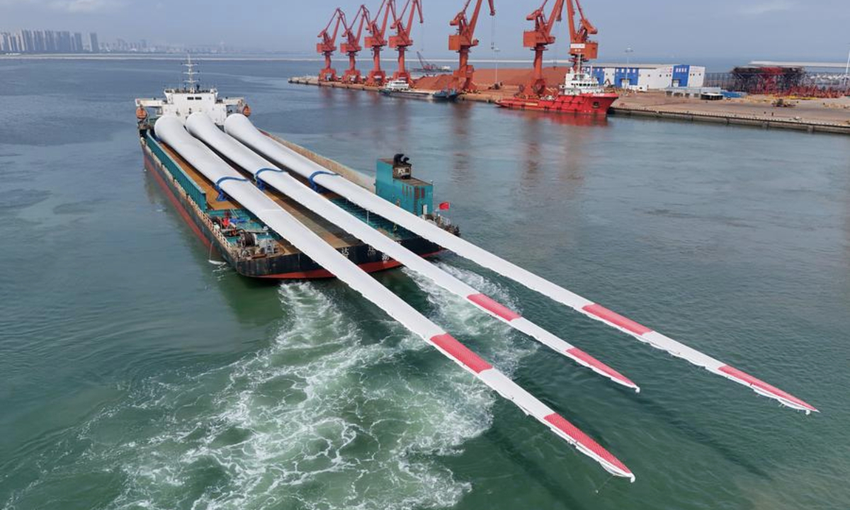 An aerial drone photo taken on Aug. 1, 2025 shows oversized offshore wind turbine blades being transported from Yantai Port in east China's Shandong Province. (Photo by Tang Ke/Xinhua)