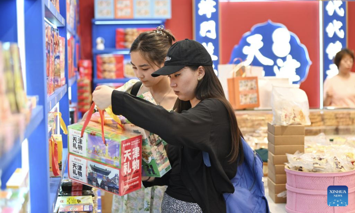 Young students from the Shanghai Cooperation Organization (SCO) countries select gifts at an ancient cultural street in north China's Tianjin, Aug. 14, 2025. Hundreds of young students from SCO countries, who are visiting China on a cultural exchange program, experienced the charm of traditional Chinese culture here on Thursday. (Xinhua/Li Ran)