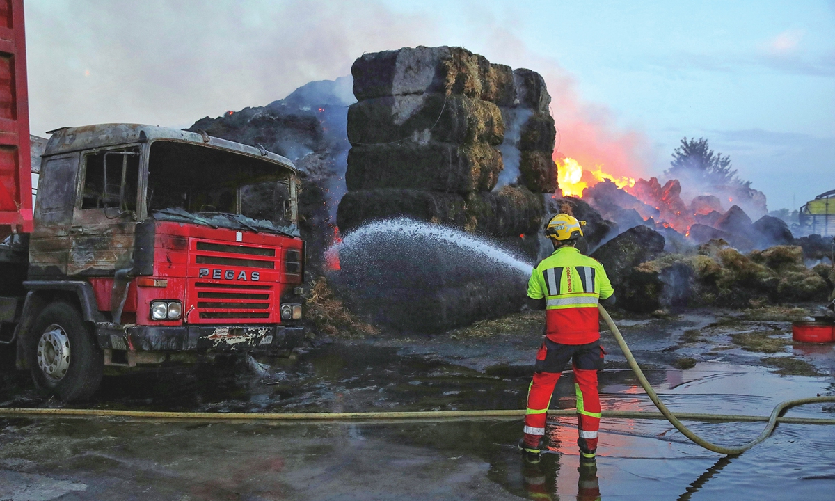A firefighter extinguishes a blaze in Spain's Toledo on August 13, 2025. Thousands of soldiers were deployed to fight multiple wildfires in Spain, where about 14 blazes were actively burning on Wednesday. Spain's national meteorological agency issued orange-level 
