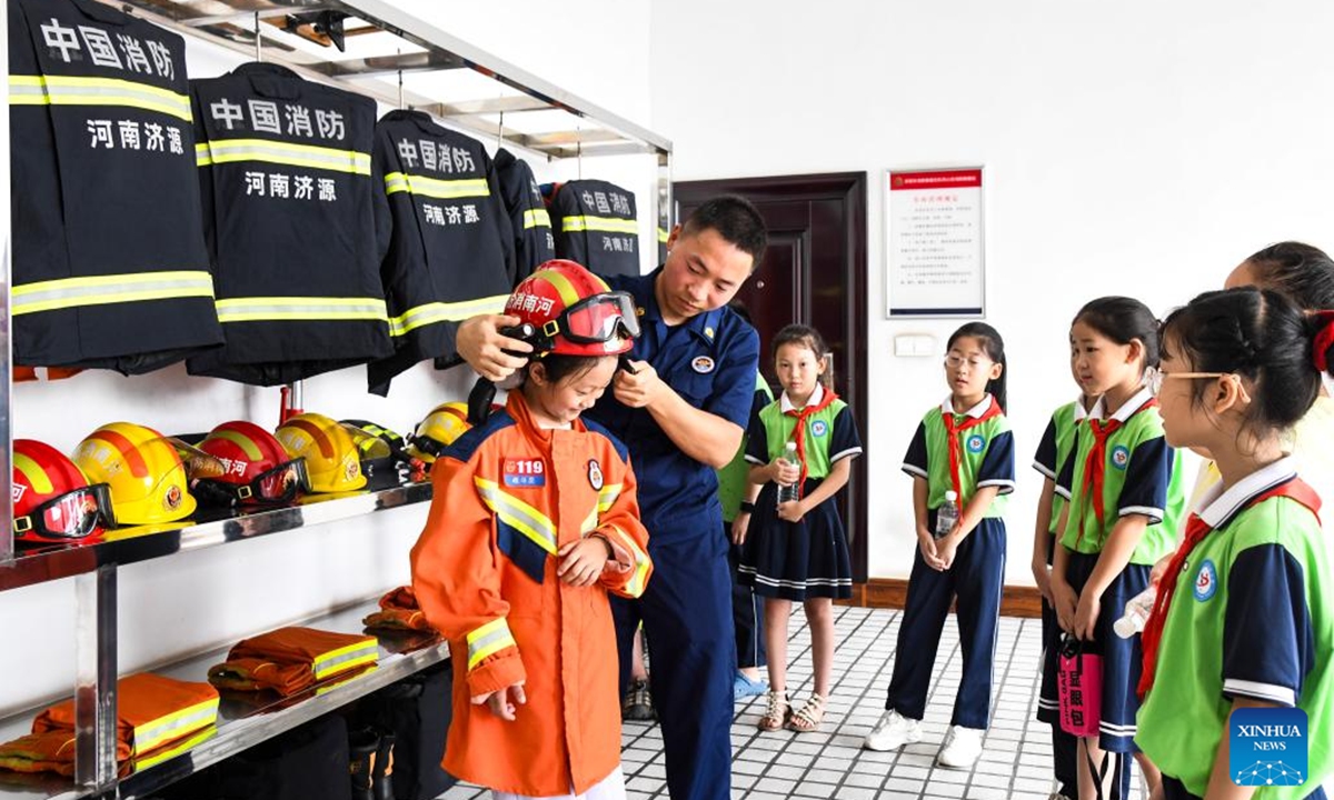 A child tries firefighting gears at a fire and rescue station in Jiyuan City, central China's Henan Province, Aug. 16, 2025. (Photo by Miao Qiunao/Xinhua)