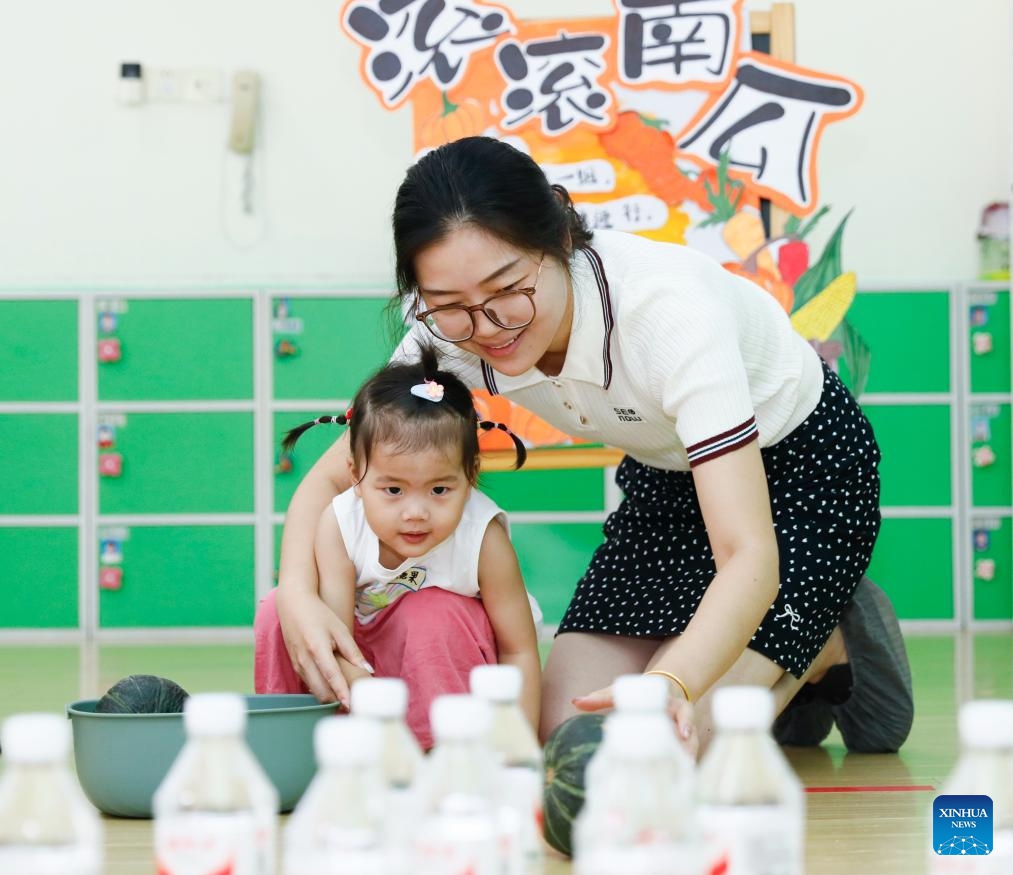 A guardian and her child play a game at a daycare center in Hai'an City, east China's Jiangsu Province, Aug. 16, 2025. (Photo by Gu Binbin/Xinhua)