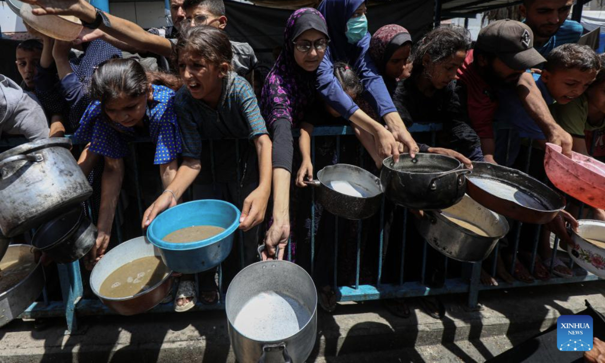 Displaced Palestinians wait to receive free food at a distribution center in Gaza City, on Aug. 18, 2025. (Photo by Rizek Abdeljawad/Xinhua)