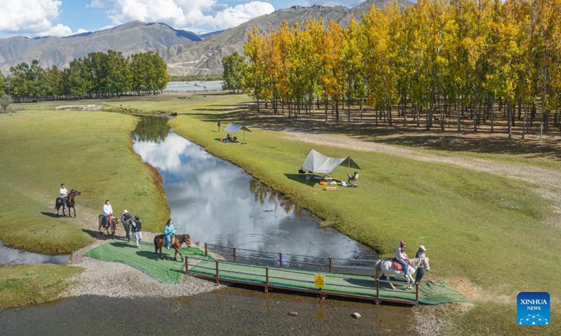 An aerial drone photo taken on Sept. 27, 2025 shows tourists riding horses at a Lingka camping site in Lhunzhub County of Lhasa, southwest China's Xizang Autonomous Region. Lingka means garden in the Tibetan language. In Xizang, people follow a tradition of spending the Lingka time during which they camp out and have picnics in parks or suburbs. Nowadays, this traditional folk custom has developed into a new form of cultural tourism as well as a vibrant lifestyle.(Xinhua/Tenzin Nyida)
