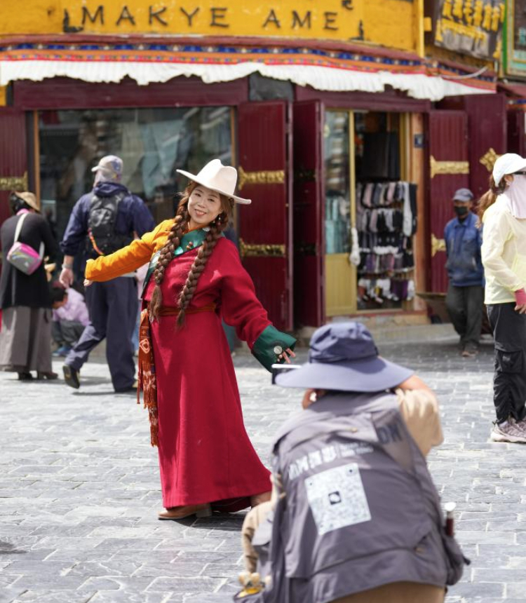 A tourist wearing Tibetan costumes poses for photos at the ancient city of Lhasa, southwest China's Xizang Autonomous Region, Aug. 19, 2025. (Xinhua/Jigme Dorje)