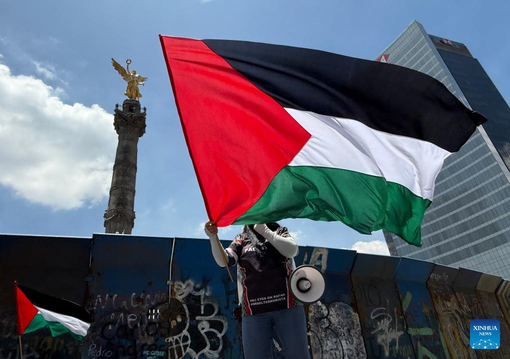 This photo taken with a mobile phone shows a protester waving the Palestinian flag to protest the ongoing war and famine in Gaza at the monument, the Angel of Independence, in Mexico City, Mexico, on Aug. 17, 2025. (Xinhua/Wu Wei)