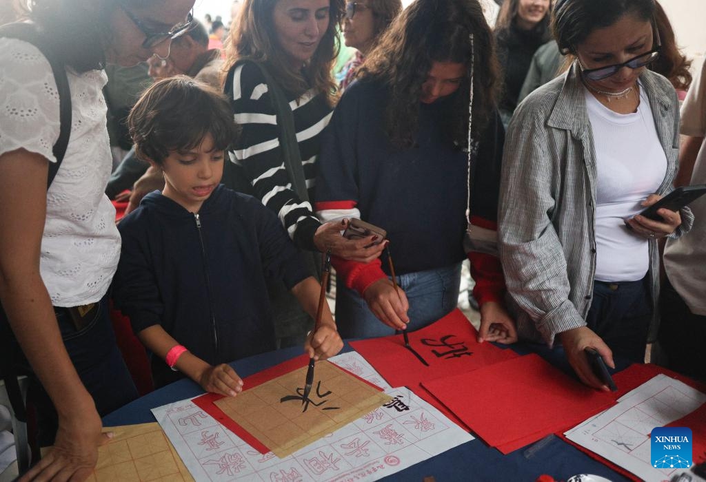 People try Chinese calligraphy during a celebration marking the 51st anniversary of China-Brazil diplomatic relations and the 80th anniversary of the victory in World War II, at Forte Copacabana in Rio de Janeiro, Brazil, Aug. 16, 2025. (Photo by Claudia Martini/Xinhua)