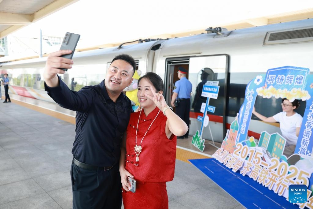 A couple pose for photos at Qiqihar South Railway Station in Qiqihar, northeast China's Heilongjiang Province, Aug. 17, 2025. On Aug. 17, 2015, the Harbin-Qiqihar railway, Heilongjiang's first high-speed railway, from the provincial capital Harbin to Qiqihar City, was put into operation and became China's northernmost of its kind in operation in the northeastern province of China. (Photo by Yuan Yong/Xinhua)