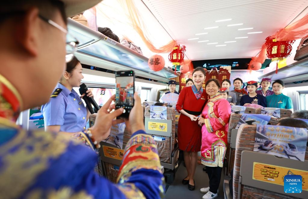 A passenger poses for photos with a high-speed train attendant on a train in northeast China's Heilongjiang Province, Aug. 17, 2025. On Aug. 17, 2015, the Harbin-Qiqihar railway, Heilongjiang's first high-speed railway, from the provincial capital Harbin to Qiqihar City, was put into operation and became China's northernmost of its kind in operation in the northeastern province of China. (Photo by Yuan Yong/Xinhua)