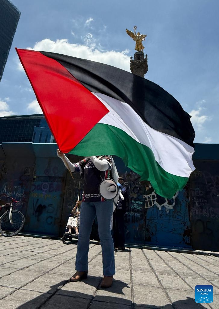 This photo taken with a mobile phone shows a protester waving the Palestinian flag to protest the ongoing war and famine in Gaza at the monument, the Angel of Independence, in Mexico City, Mexico, on Aug. 17, 2025. (Xinhua/Wu Wei)