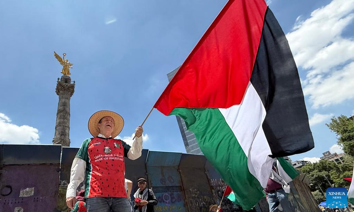 This photo taken with a mobile phone shows a protester waving the Palestinian flag to protest the ongoing war and famine in Gaza at the monument, the Angel of Independence, in Mexico City, Mexico, on Aug. 17, 2025. (Xinhua/Wu Wei)