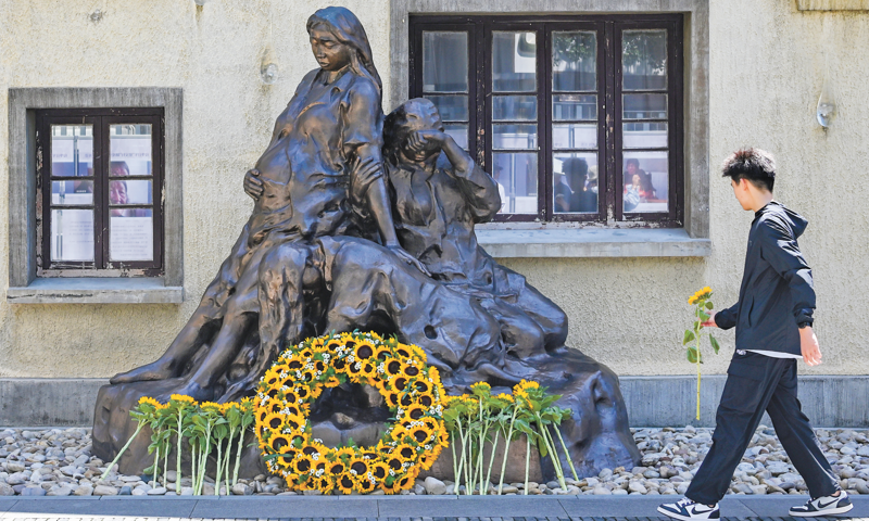 A citizen offers a flower to a sculpture dedicated to the 