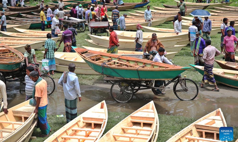 People shop for hand-made wooden boats at a traditional market in Manikganj, Bangladesh, on Aug. 20, 2025. Waterways play a vital role in communications in Bangladesh, where traditional country boats and small vessels continue to offer affordable and convenient transport. (Photo by Habibur Rahman/Xinhua)