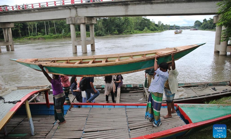 People transport a hand-made wooden boat in Manikganj, Bangladesh, on Aug. 20, 2025. Waterways play a vital role in communications in Bangladesh, where traditional country boats and small vessels continue to offer affordable and convenient transport. (Photo by Habibur Rahman/Xinhua)