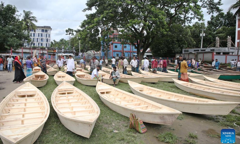 People shop for hand-made wooden boats at a traditional market in Manikganj, Bangladesh, on Aug. 20, 2025. Waterways play a vital role in communications in Bangladesh, where traditional country boats and small vessels continue to offer affordable and convenient transport. (Photo by Habibur Rahman/Xinhua)