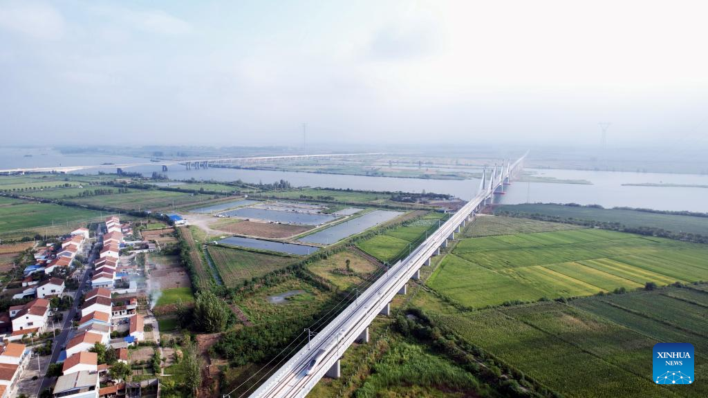 An aerial drone photo taken on Aug. 23, 2025 shows a test train running on the Xiangyang-Jingmen high-speed railway in central China's Hubei Province. The Xiangyang-Jingmen high-speed railway started test operation on Saturday. Connecting Xiangyang City of central China's Hubei Province in the north and Jingmen City of the province in the south, the 116.23-km-long railway with a designed speed of 350 kilometers per hour is an important section in one of the main passages of a greater high-speed rail artery network consisting eight vertical lines and eight horizontal lines in the country. (Photo by Chen Long/Xinhua)