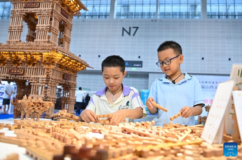 Children play toys based on Sunmao, or Chinese joints, a traditional Chinese method of connecting wood, at the 7th Shanxi Cultural Industries Fair in Taiyuan, north China's Shanxi Province, Aug. 21, 2025. The fair kicked off here on Thursday and will last till Aug. 25, attracting about 2,000 exhibitors from over 30 countries and regions worldwide. Photo: Xinhua