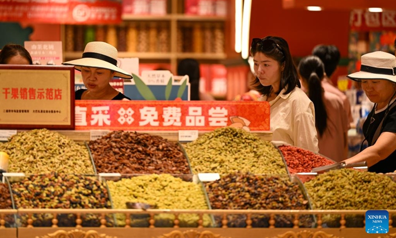 Tourists select nuts and dried fruit at the Grand Bazaar in Urumqi, northwest China's Xinjiang Uygur Autonomous Region, Aug. 21, 2025. Scenic areas across China have entered peak season for tourism. The Grand Bazaar receives an average of more than 200,000 daily tourists since July this year. Photo: Xinhua