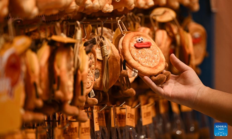 A tourist selects cultural and creative products at the Grand Bazaar in Urumqi, northwest China's Xinjiang Uygur Autonomous Region, Aug. 21, 2025. Scenic areas across China have entered peak season for tourism. The Grand Bazaar receives an average of more than 200,000 daily tourists since July this year. Photo: Xinhua