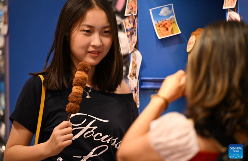 A woman poses for photos holing a cultural and creative product at the Grand Bazaar in Urumqi, northwest China's Xinjiang Uygur Autonomous Region, Aug. 21, 2025. Scenic areas across China have entered peak season for tourism. The Grand Bazaar receives an average of more than 200,000 daily tourists since July this year. Photo: Xinhua