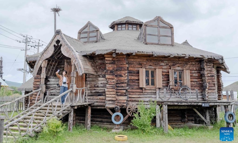 A tourist takes selfie in front of a distinctive Russian-style wooden house at Enhe Township of Hulun Buir, north China's Inner Mongolia Autonomous Region, on Aug. 21, 2025. Enhe, located in the northeastern corner of Inner Mongolia, is China's only Russian ethnic township that has for years drawn travelers seeking its inspiring blend of Chinese-Russian culture, hearty cuisine and sweeping natural vistas.

In recent years Enhe has attracted many tourists by promoting unique activities such as local family visiting, Russian bread making and Matryoshka doll painting.

The township, with a population of only about 2,900, received 615,000 visitors in 2024, who had brought in a gross tourism revenue of 92.25 million yuan (about 12.85 million U.S. dollars). Photo: Xinhua