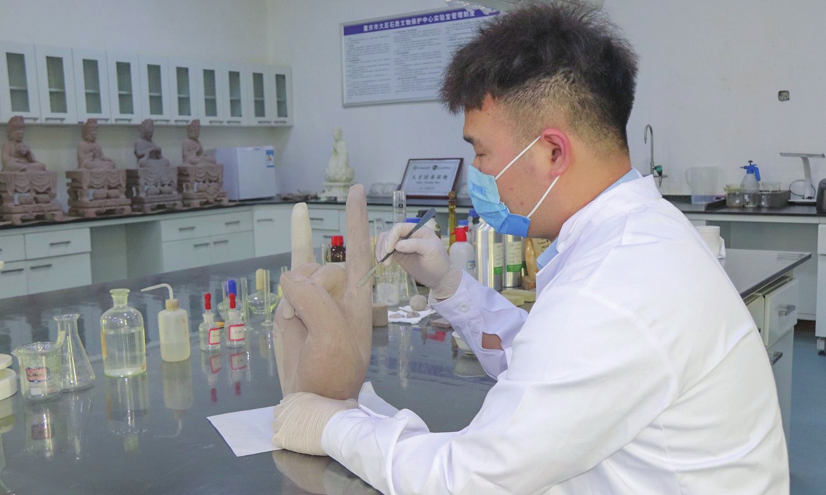 A researcher restores a sample of a Buddhist hand artifact Photo: Courtesy of Chongqing University 