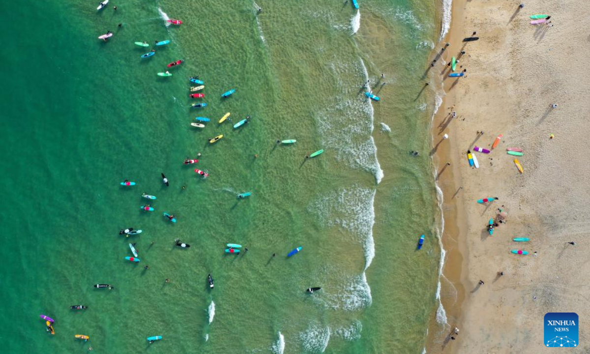 An aerial drone photo shows tourists surfing at Riyue Bay in Wanning, south China's Hainan Province, Oct. 2, 2025. Surfing has become a symbol of Wanning thanks to its unique geographical and climatic advantages. (Xinhua/Guo Cheng)