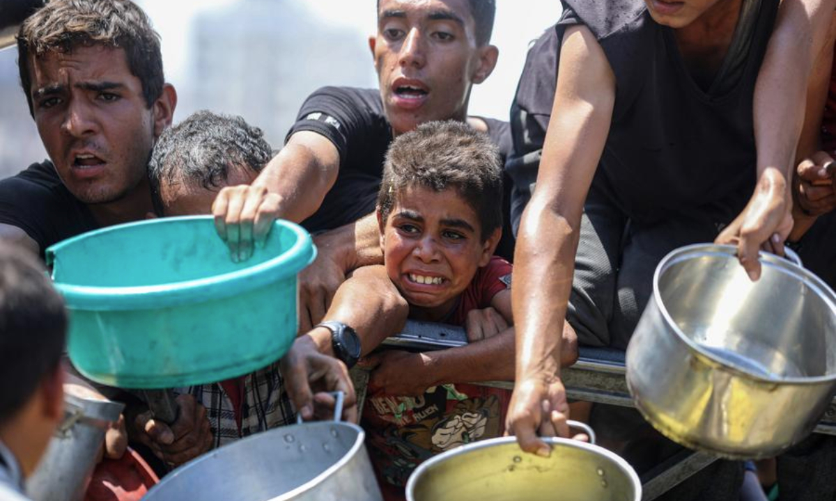 Palestinians wait to receive free food at a camp for displaced people in southwest Gaza City, on Aug. 24, 2025. (Photo by Rizek Abdeljawad/Xinhua)