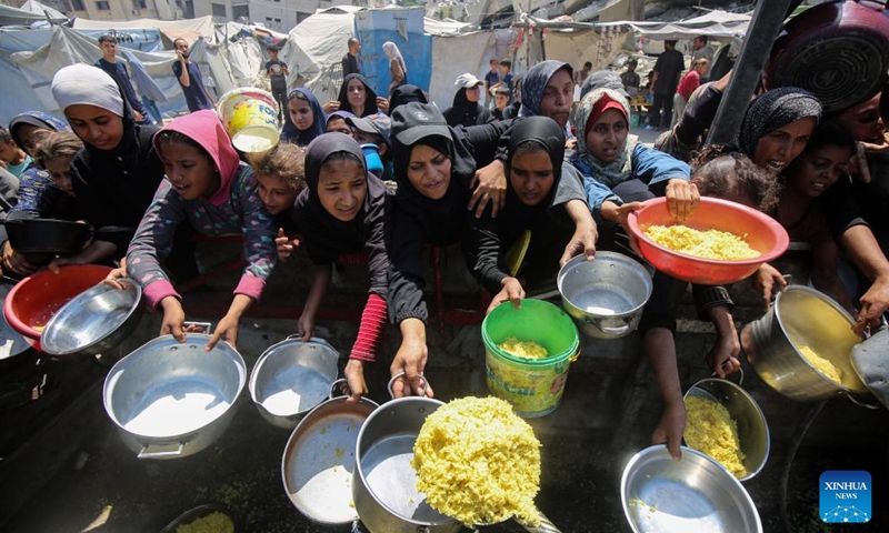 Palestinians wait to receive free food at a camp for displaced people in southwest Gaza City, on Aug. 24, 2025. (Photo by Rizek Abdeljawad/Xinhua)