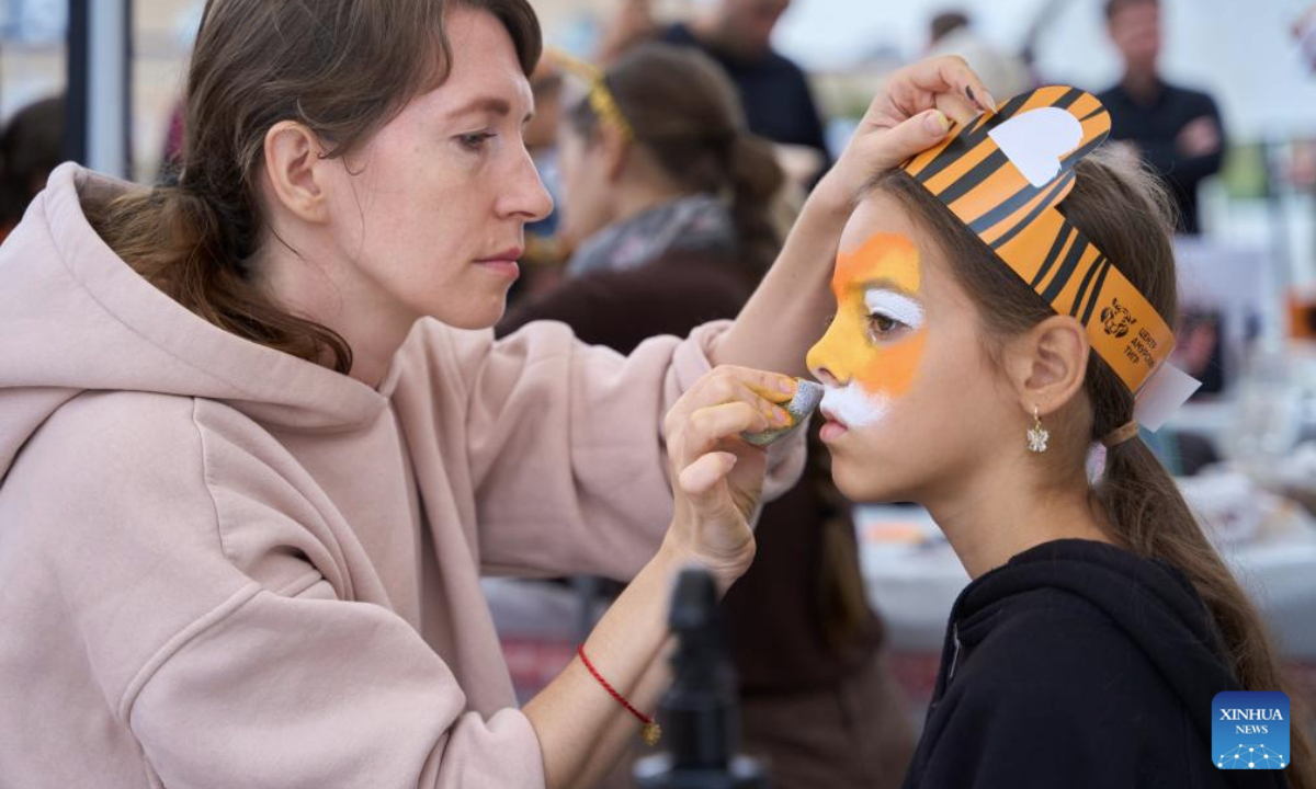 A girl gets make-up during the Tiger Day event in Vladivostok, Russia, Sept. 28, 2025. Since 2000, Vladivostok has celebrated Tiger Day in the last weekend of September each year to raise public awareness about tiger conservation. (Photo by Guo Feizhou/Xinhua)