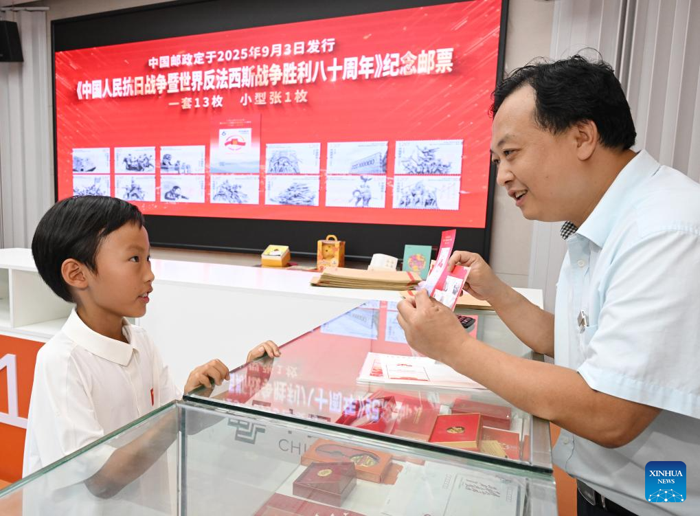 A staff member introduces the commemorative stamps issued by China Post to mark the 80th anniversary of the victory in the Chinese People's War of Resistance Against Japanese Aggression and the World Anti-Fascist War at a stamp company in Beijing, capital of China, Sept. 3, 2025. A total of six million stamp sets were issued, with each set containing 13 stamps. Five million miniature sheets were also issued. (Xinhua/Li He)