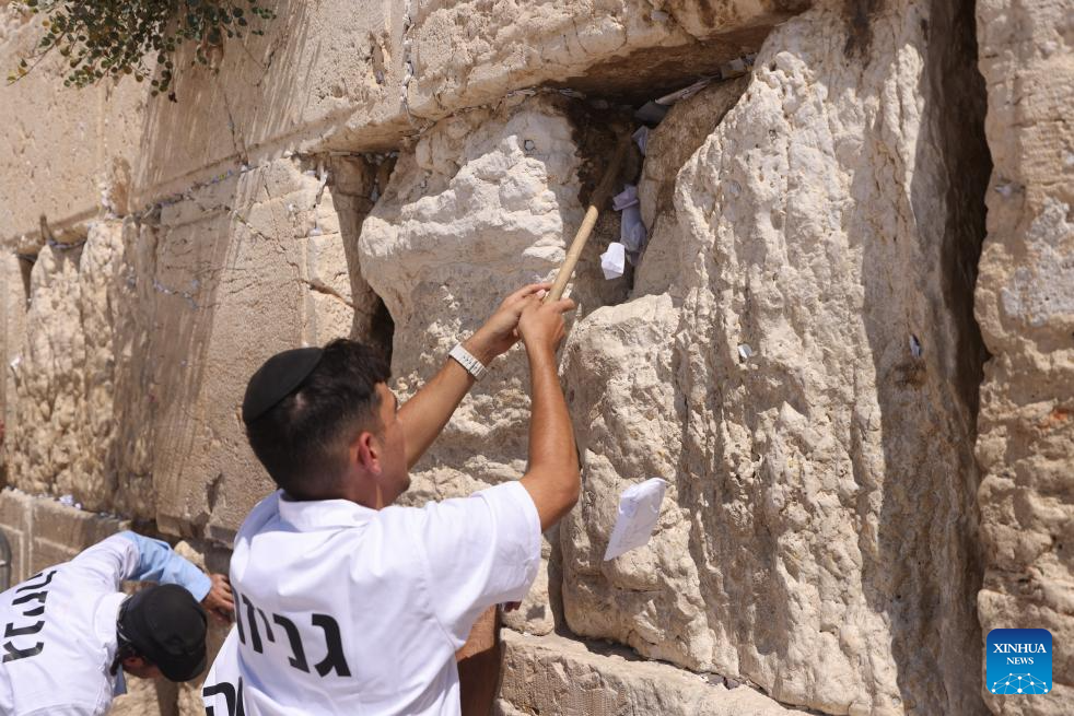 Staff members remove notes from the cracks of the Western Wall in Jerusalem's Old City on Sept. 16, 2025. According to the Jewish tradition, notes left in the Western Wall by worshipers and tourists are removed and respectfully buried before the Jewish New Year to make space for new ones. Each year, hundreds of thousands of such notes bearing blessings and wishes are placed in the Western Wall's cracks by visitors from around the world. (Photo by Jamal Awad/Xinhua)