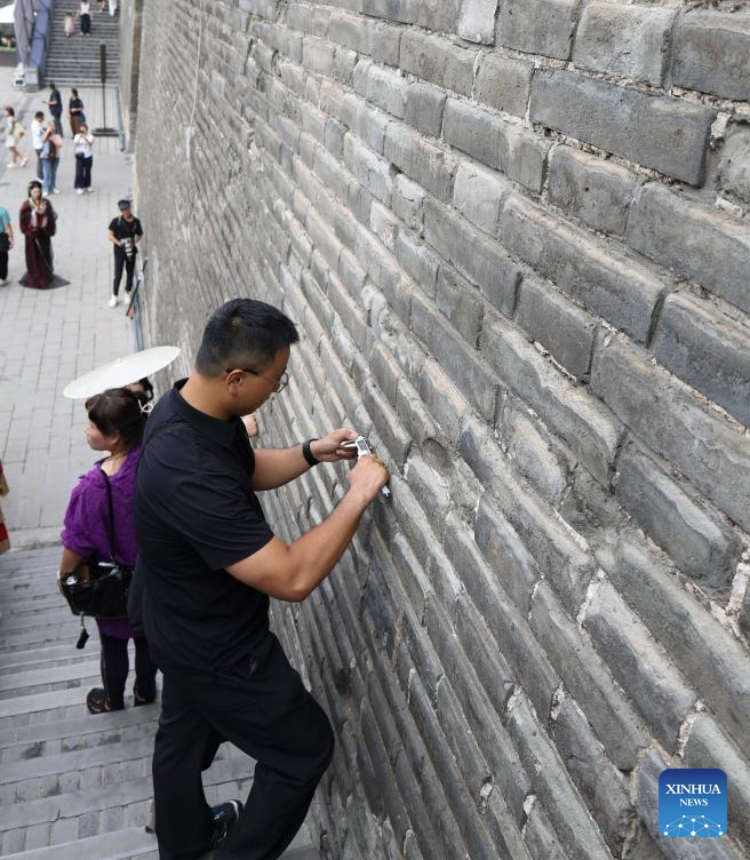 An inspector measures the length of a crack on the ancient city wall in Xi'an, northwest China's Shaanxi Province, Sept. 10, 2025. The 13.74-kilometer-long ancient city wall that surrounds Xi'an is one of the longest and best-preserved of its kind in China. A digital comprehensive management platform has been built for the wall since 2023, which integrates functions such as cultural relic protection, cultural tourism operation, emergency management, and flood-control command.
By comprehensively applying advanced technologies including big data analysis, Internet of Things, etc., the platform provides a digital and intelligent foundation for the protection of this historic city. (Xinhua/Zhu Weixi)