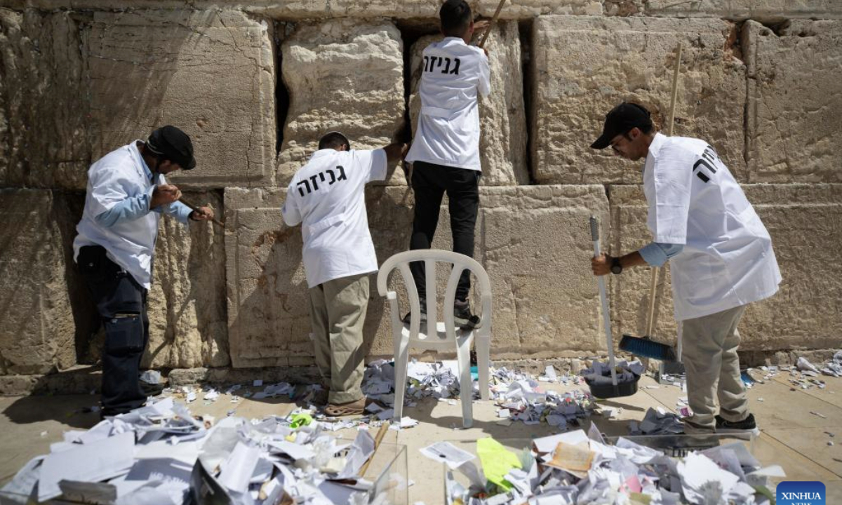 Staff members remove notes from the cracks of the Western Wall in Jerusalem's Old City on Sept. 16, 2025. According to the Jewish tradition, notes left in the Western Wall by worshipers and tourists are removed and respectfully buried before the Jewish New Year to make space for new ones. Each year, hundreds of thousands of such notes bearing blessings and wishes are placed in the Western Wall's cracks by visitors from around the world. (Xinhua/Chen Junqing)