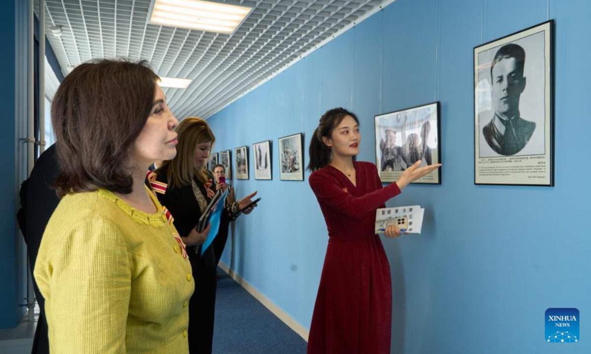 A staff member introduces a photo to visitors at a photo exhibition commemorating the 80th anniversary of the victory in the Chinese People's War of Resistance against Japanese Aggression and the World Anti-Fascist War in Vladivostok, Russia, Sept. 2, 2025. (Photo by Guo Feizhou/Xinhua)