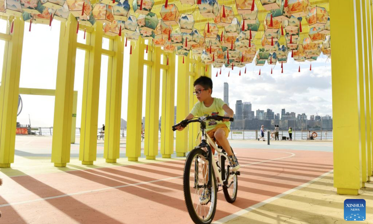 A boy rides past decorative lanterns in south China's Hong Kong, Sept. 27, 2025. With the approach of National Day and the Mid-Autumn Festival, the streets of Hong Kong are adorned with festive decorations. (Xinhua/Chen Duo)