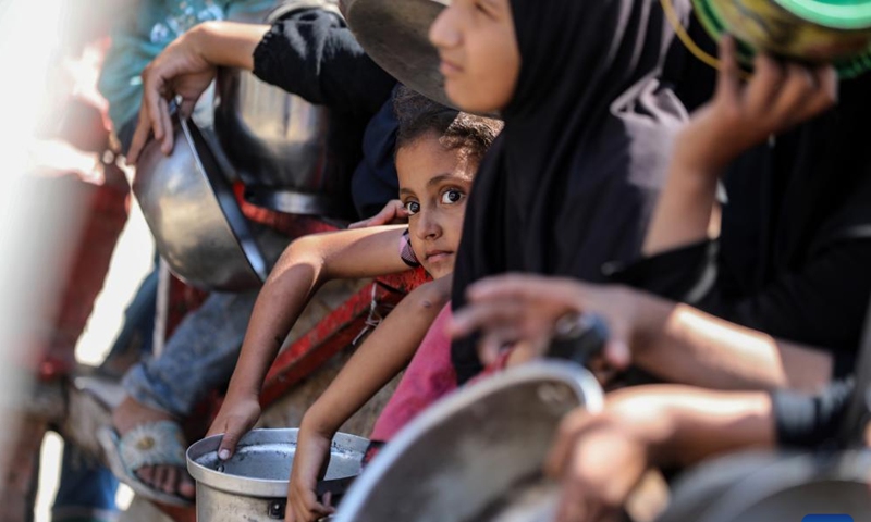 Palestinians wait to receive free food at a camp for displaced people in southwest Gaza City, on Aug. 24, 2025. (Photo by Rizek Abdeljawad/Xinhua)